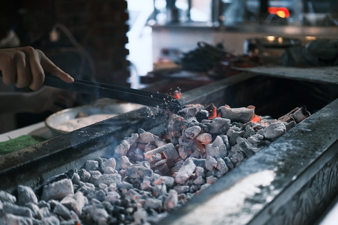 a-person-cooking-food-on-a-grill-in-a-kitchen-kvm6dy9ebms