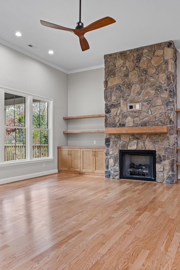 Contemporary living room interior featuring a stone fireplace and wooden flooring.